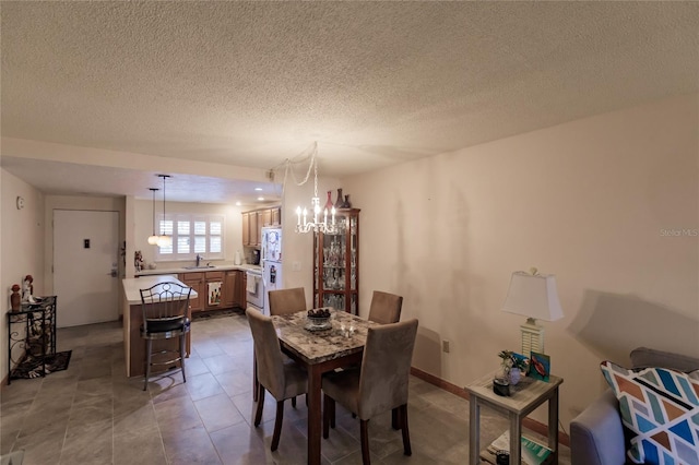 dining space with a chandelier, light tile patterned floors, a textured ceiling, and sink