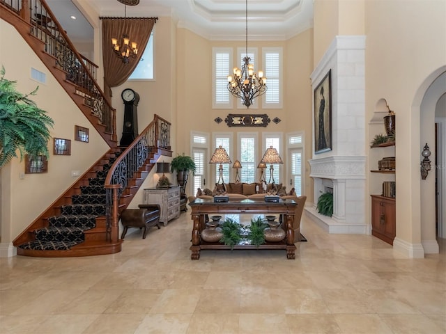 interior space featuring a fireplace, a chandelier, a high ceiling, and ornamental molding