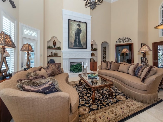 living room featuring a fireplace, a towering ceiling, plenty of natural light, and a notable chandelier