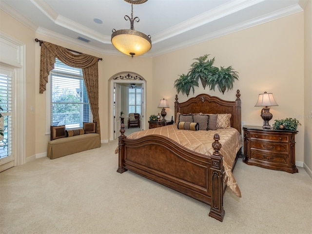 bedroom featuring a tray ceiling, light colored carpet, and ornamental molding