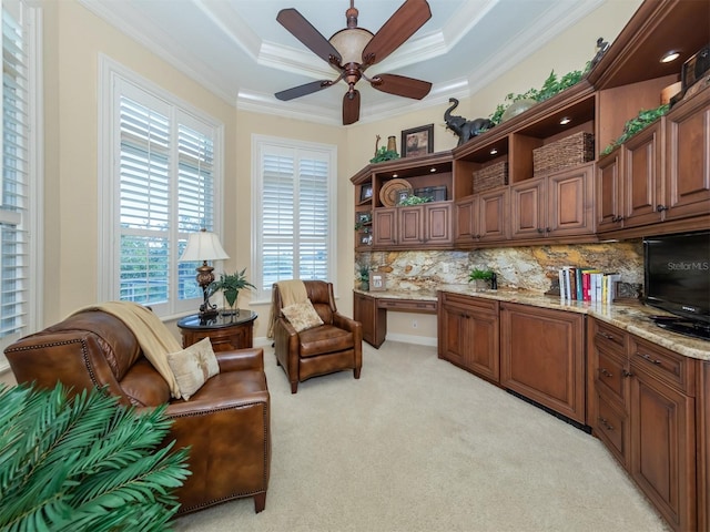 interior space featuring built in desk, a tray ceiling, ceiling fan, and crown molding