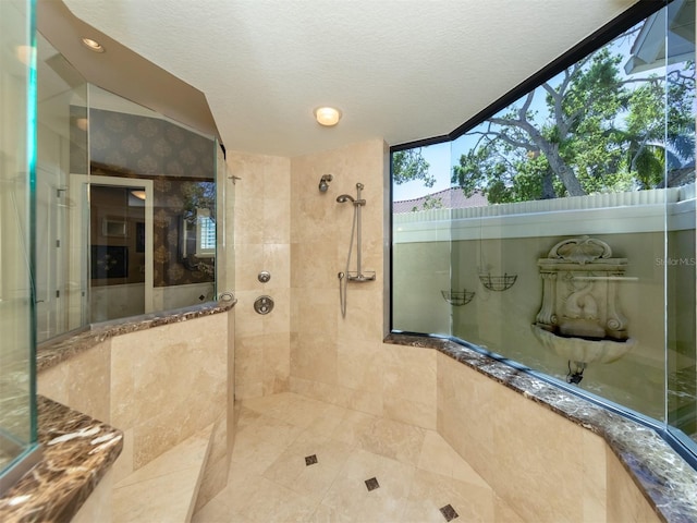 bathroom with a textured ceiling and tiled shower