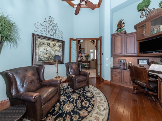 office space featuring ceiling fan, french doors, dark hardwood / wood-style floors, a towering ceiling, and built in desk