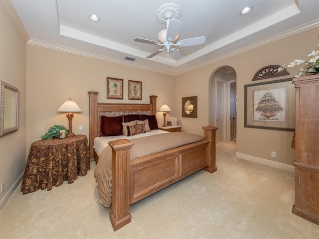 bedroom featuring a raised ceiling, ceiling fan, crown molding, and light colored carpet