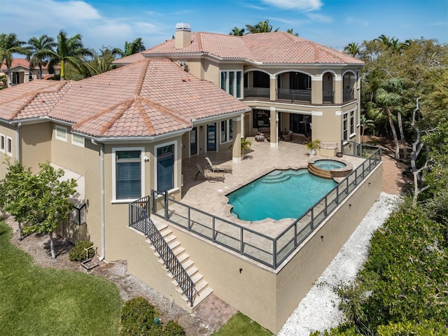 rear view of house featuring a patio area, a balcony, and a pool with hot tub