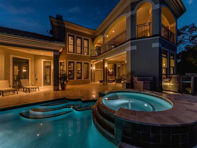 pool at twilight with an in ground hot tub, french doors, and a patio