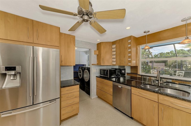 kitchen with dark stone countertops, sink, stainless steel appliances, and washing machine and clothes dryer