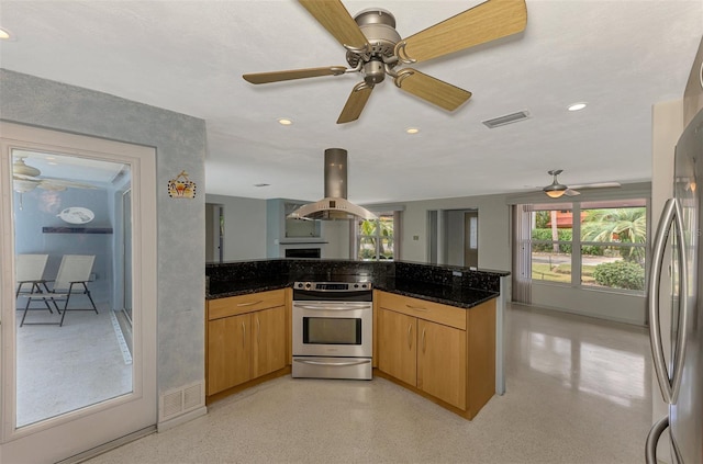 kitchen with island exhaust hood, stainless steel appliances, ceiling fan, and dark stone countertops