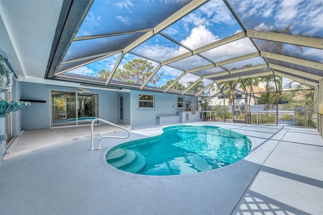 view of pool with glass enclosure and a patio