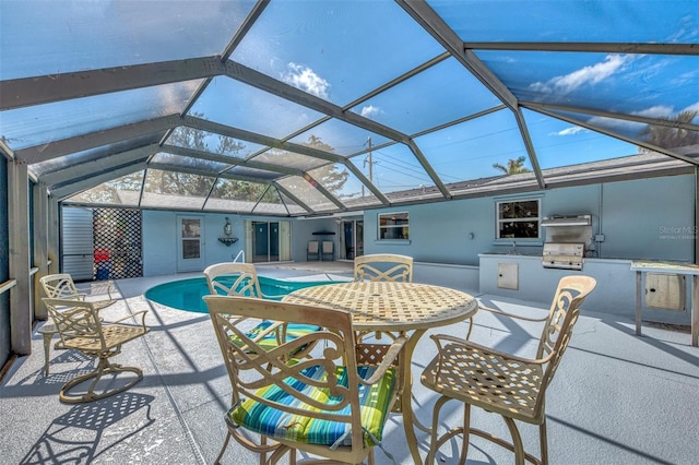 view of pool with an outdoor kitchen, a grill, a patio, and glass enclosure