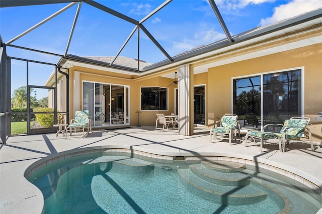 view of swimming pool featuring glass enclosure and a patio