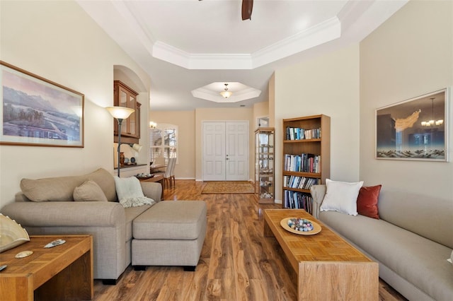 living room with a tray ceiling, dark hardwood / wood-style floors, ornamental molding, and ceiling fan