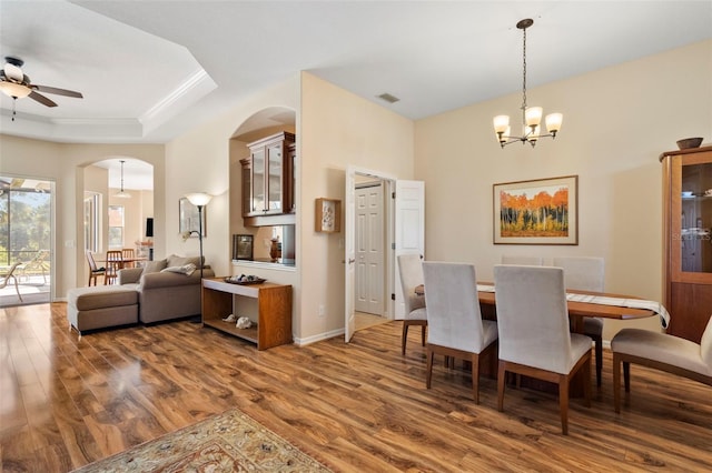 dining room with hardwood / wood-style floors, ceiling fan with notable chandelier, and a tray ceiling