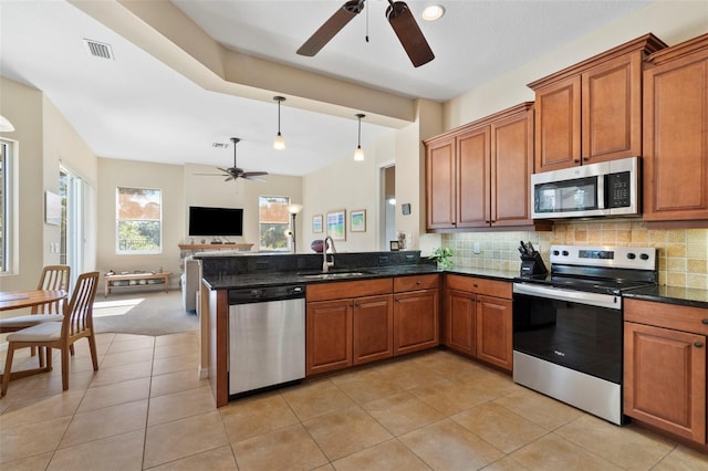 kitchen with sink, stainless steel appliances, kitchen peninsula, dark stone countertops, and decorative backsplash