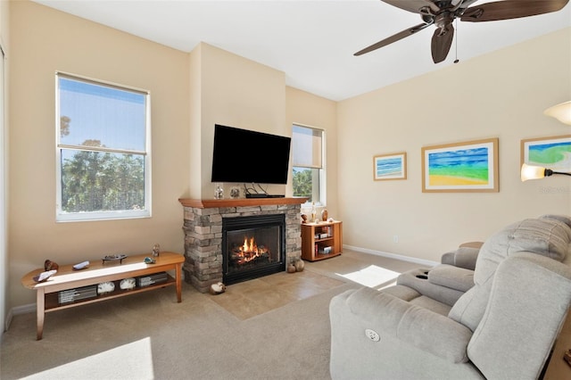 living room featuring light colored carpet, a stone fireplace, and ceiling fan