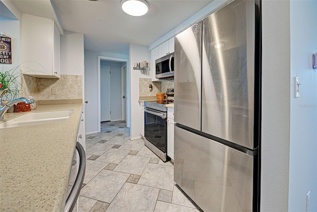 kitchen with decorative backsplash, white cabinetry, sink, and appliances with stainless steel finishes