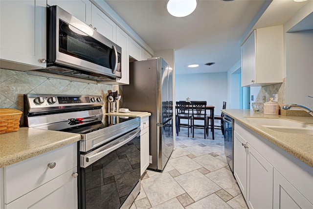 kitchen featuring decorative backsplash, white cabinetry, sink, and appliances with stainless steel finishes