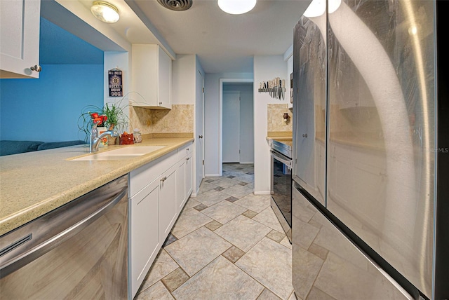 kitchen featuring white cabinetry, decorative backsplash, sink, and stainless steel appliances