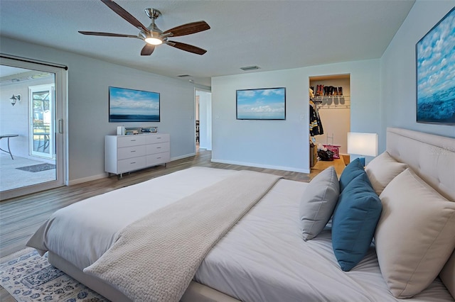 bedroom featuring hardwood / wood-style floors, a walk in closet, ceiling fan, access to exterior, and a closet