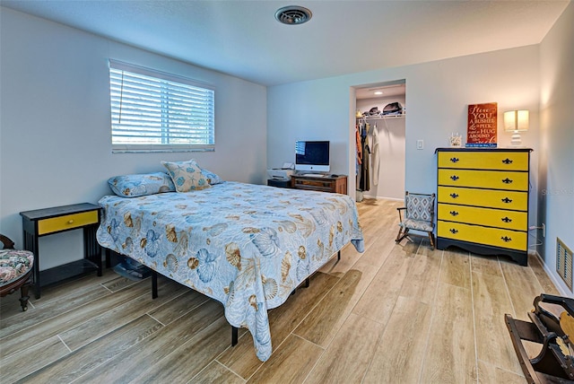 bedroom featuring a spacious closet, a closet, and hardwood / wood-style floors