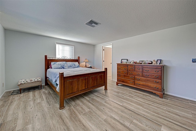 bedroom with a textured ceiling and light wood-type flooring