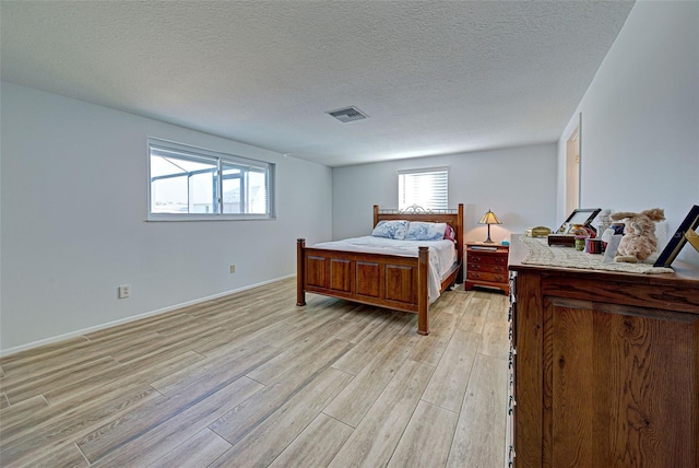 bedroom with a textured ceiling and light wood-type flooring