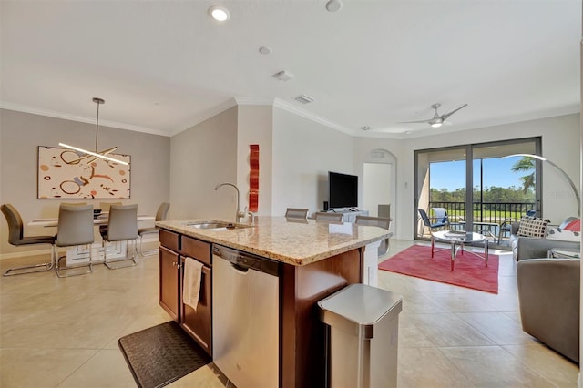 kitchen featuring dishwasher, a center island with sink, sink, hanging light fixtures, and light stone counters