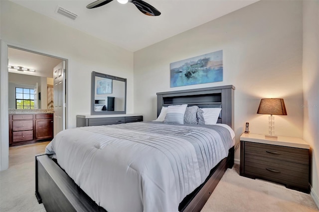 carpeted bedroom with ensuite bath and ceiling fan