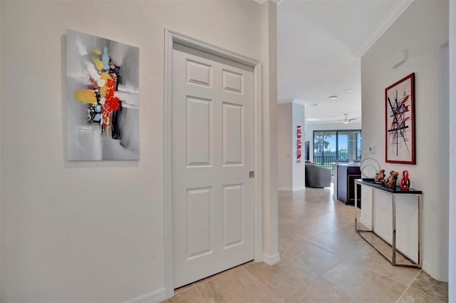 hallway with light tile patterned floors and crown molding