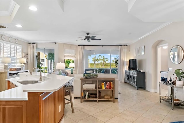 kitchen with ceiling fan, a kitchen island with sink, crown molding, and sink