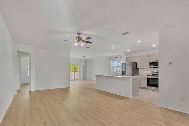 kitchen with a center island, light hardwood / wood-style floors, appliances with stainless steel finishes, ceiling fan, and sink