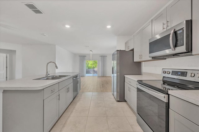 kitchen with sink, stainless steel appliances, an island with sink, and light tile patterned flooring