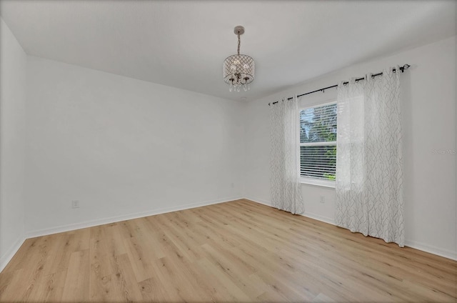 unfurnished room featuring an inviting chandelier and light wood-type flooring