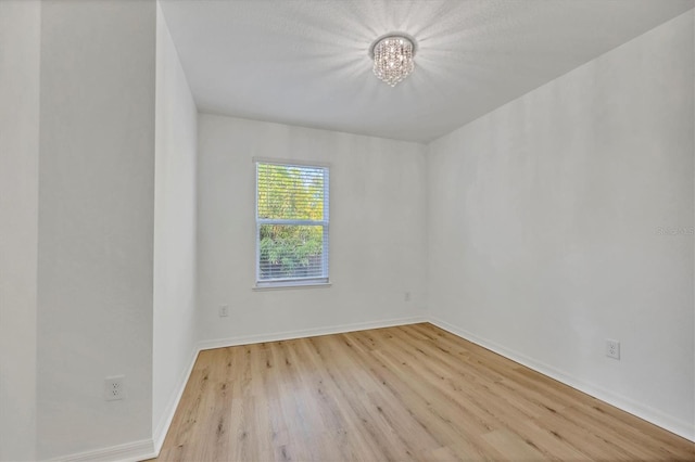 empty room featuring a chandelier and light hardwood / wood-style floors