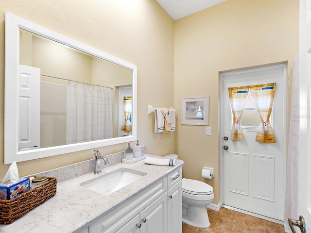 bathroom featuring tile patterned flooring, vanity, toilet, and walk in shower