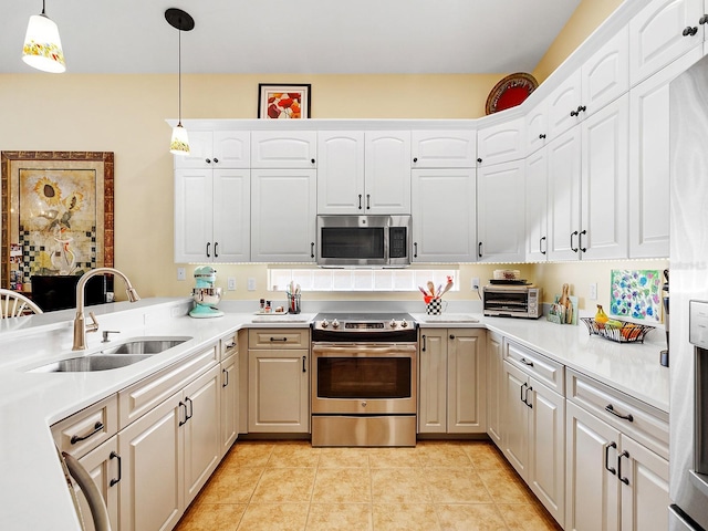 kitchen with hanging light fixtures, sink, light tile patterned floors, appliances with stainless steel finishes, and white cabinetry