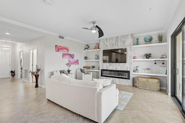 living room with built in shelves, crown molding, a large fireplace, and ceiling fan with notable chandelier