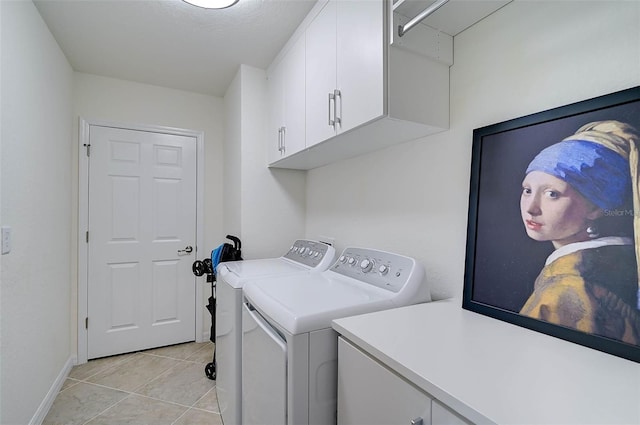 clothes washing area featuring cabinets, light tile patterned floors, and washer and clothes dryer