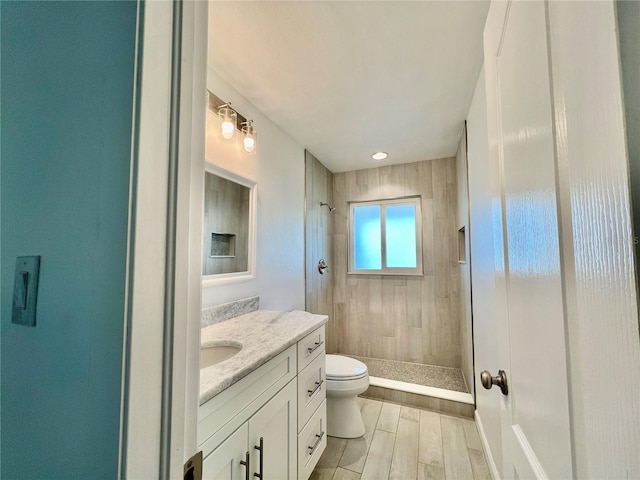 bathroom featuring vanity, toilet, and a tile shower