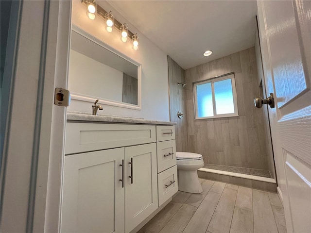 bathroom with vanity, toilet, and tiled shower