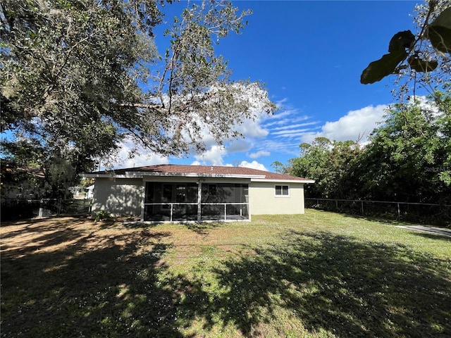 rear view of property with a lawn and a sunroom