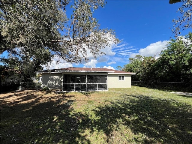 rear view of property with a lawn and a sunroom