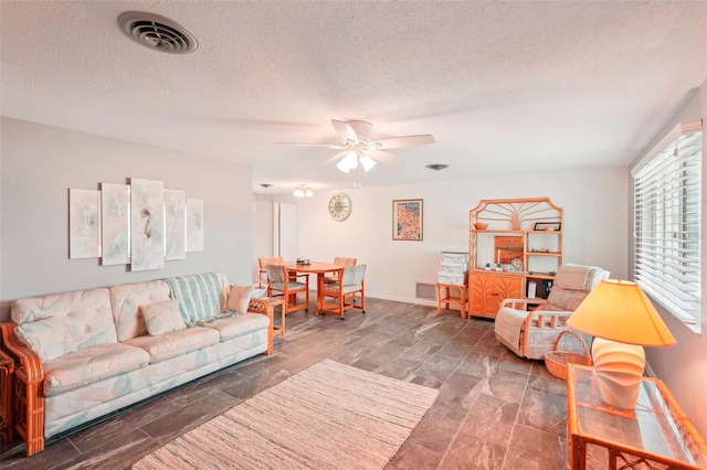 living room featuring ceiling fan and a textured ceiling