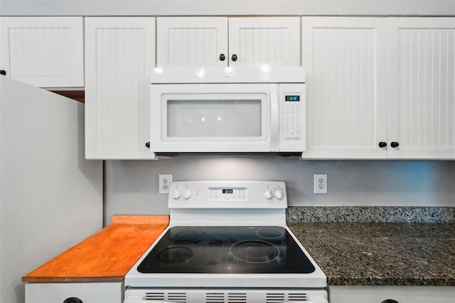 kitchen with white appliances, white cabinetry, and dark stone countertops