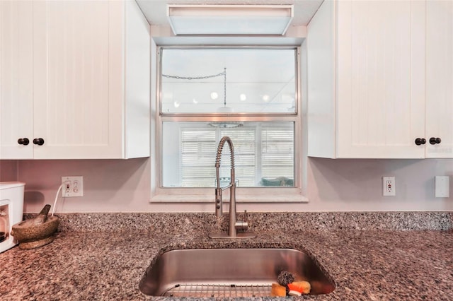 details with white cabinets, stone countertops, and sink