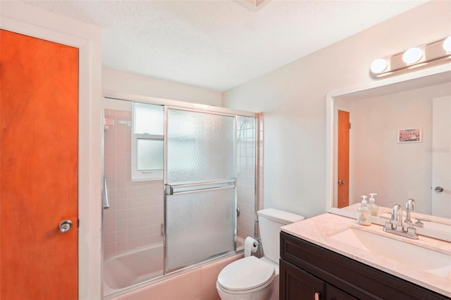 full bathroom with shower / bath combination with glass door, vanity, a textured ceiling, and toilet