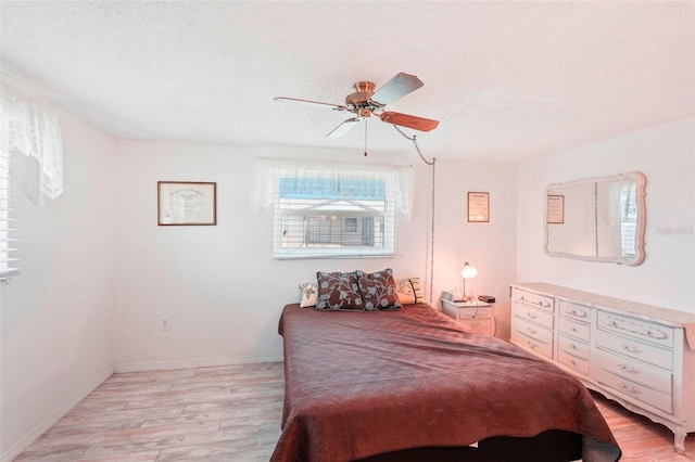 bedroom featuring light wood-type flooring, a textured ceiling, and ceiling fan