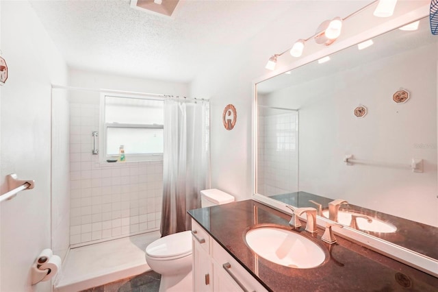 bathroom featuring toilet, vanity, a textured ceiling, and walk in shower