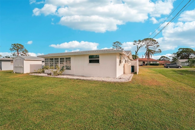 rear view of property featuring a sunroom, a shed, and a lawn