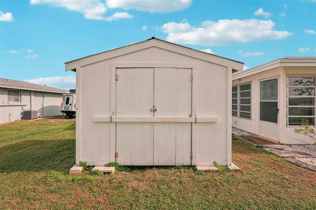 view of outdoor structure with central AC unit and a lawn